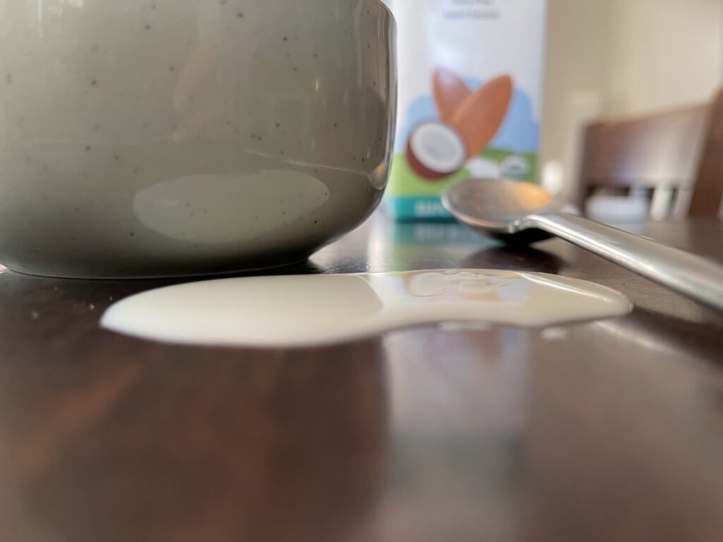 A puddle of spilled almond milk next to a bowl.
