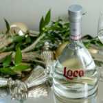 A bottle of Loco Tequila in front of seasonal ornaments