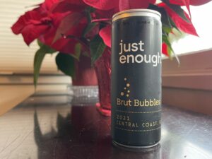 250 ml can of Just Enough Brut Bubbles in front of a poinsettia.