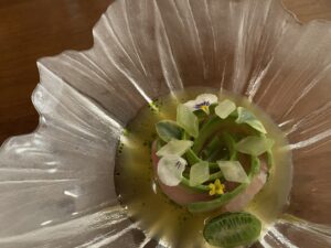 Japanese kampachi with aguachile on a translucent plate.