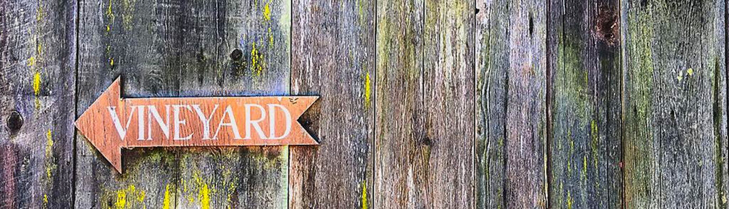An arrow on an old wooden fence pointing to Anderson Valley vineyards