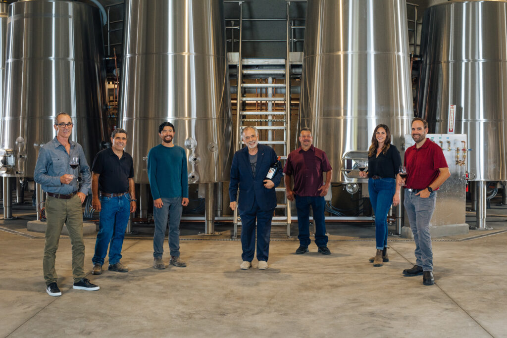 Francis Ford Coppola and the winemaking team at Inglenook stand in front of the ginormous fermentation tanks in the winery's new wine caves.
