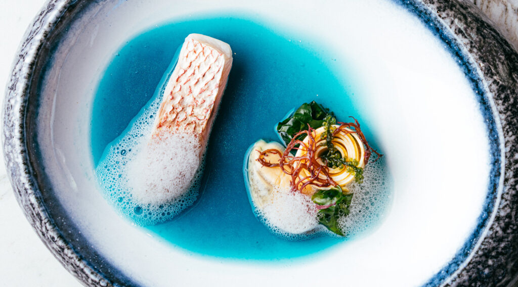 thalassa, named for the Greek goddess of the sea, a scallop dish with bright blue "Seawater" at Luce in San Francisco