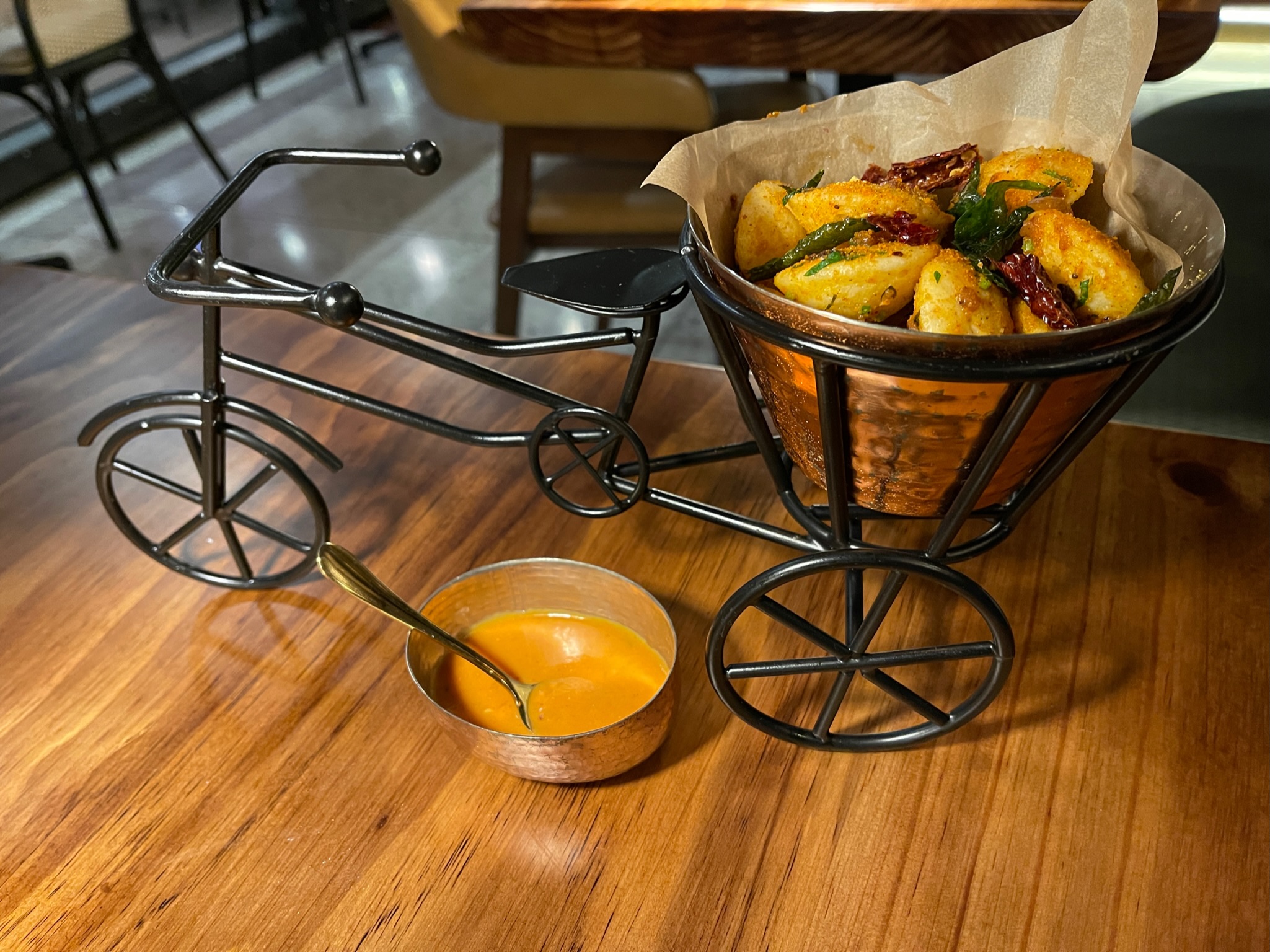 Idli (fluffy fermented rice and lentil dumplings) are served in the wire basket of a wire bike sulpture at Emeryville's, Pippal restaurant
