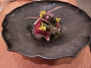 golden osetra caviar with venison-wrapped tartare on a grey plate