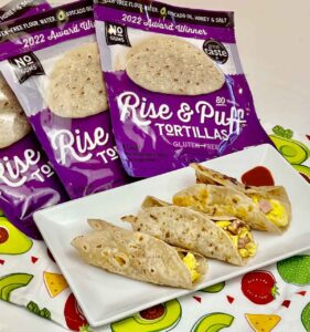 packages of Rise & Puff gluten-free tortillas behind three tortillas stuffed with eggs and bacon