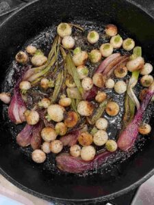 cooked red torpedo onions and Tokyo turnips in a cast iron pan