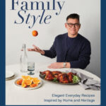 cookbook author Peter Som tosses an apple in front of a table laid with plated oranges and chicken