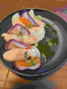 halibut crudo with citrus and radish on a black dish at Fifty Vara a San Francisco restaurant in Inner Sunset