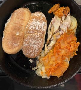 kimchi Philly cheesesteak cooking in a cast iron pan with vibrant orange carrot kimchi from Altamont General Store