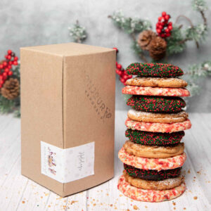A stack of Bonjour Bakehouse cookies are lined up next to the box they are shipped in