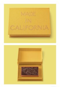 a handmade, cloth-wrapped box that features a fine-art reproduction of Ruscha’s, Made in California (1971), courtesy of the artist and Gagosian.