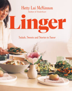 Linger by Hetty Lui MicKinnon cookbook cover shows McKinnon standing over a full table of yumminess.