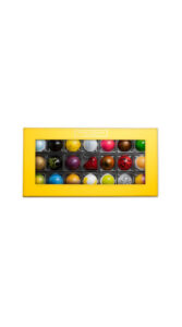Shekkoh Confections 21-piece Hemispheres Collection is 21 colorful bonbons in a yellow box with a clear lid