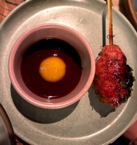 overhead image of a tsukune chicken skewer with egg yolk tare