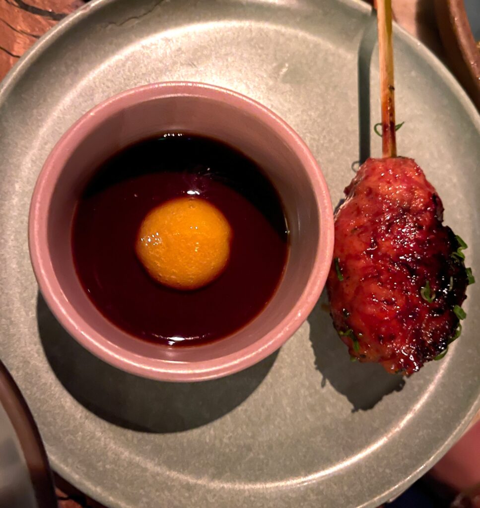 overhead image of a tsukune chicken skewer with egg yolk tare