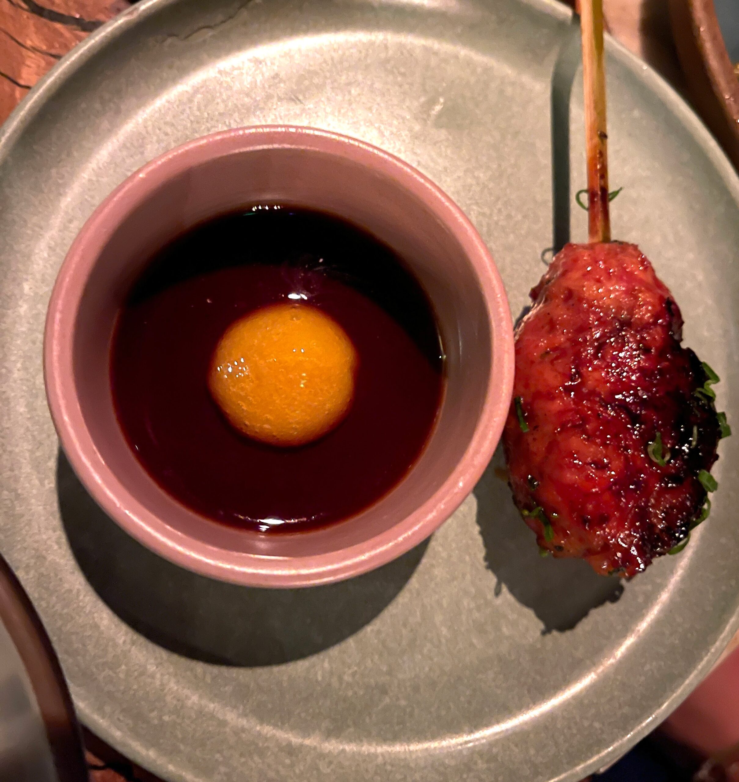 overhead image of a tsukune chicken skewer with egg yolk tare