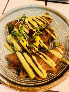 empanadas on a plate drizzled with yellow aji amarillo sauce at XICA restaurant San Francisco