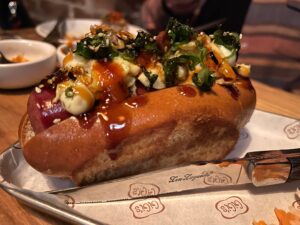 hot dog with tons of toppings dripping over the bun