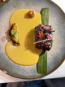 pool of bright yellow curry holds the taco and the fish is above a green stripe of curry