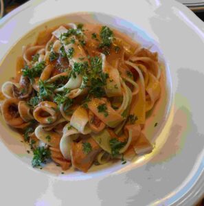 white dish with gluten-free tagliatelle pasta and calamari
