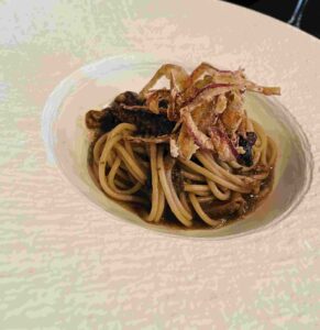 white bowl of gluten-free pasta with morels and onions
