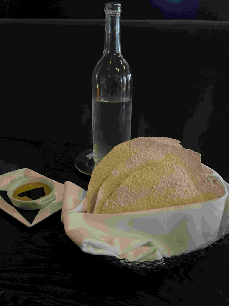 a water bottle, dish of olive oil, and bread basket with gluten-free papadums are just one option at La Toque, one of many gluten-free restaurants.