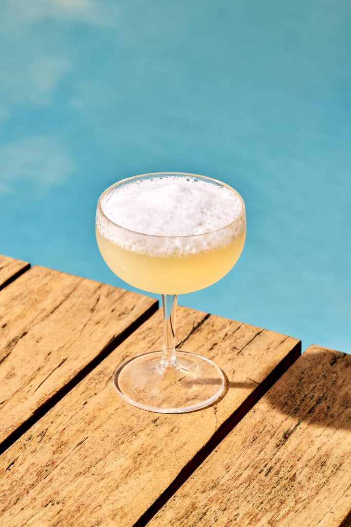 salt air margarita atop wood blanks (a dock?) with a blue sea background