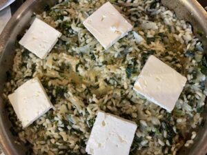 squares of feta sit atop a dish of spinach and rice