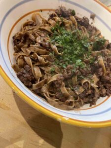 lamb and pappardelle noodles in a striped bowl