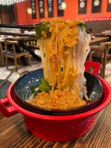 noodles with crabmeat look like a waterfall over a red bowl at Fusion Dumpling restaurant in San Francisco's Chinatown 