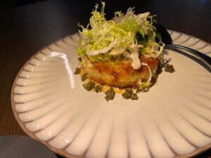 jumbo lump crabcake topped with frisee on a scallop-edged dish at BOA Steakhouse in Napa