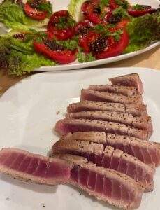 seared tuna slices in front of a tomato and lettuce salad topped with salsa