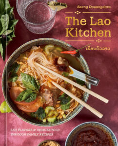 cookbook cover of The Lao Kitchen by Saeng Douangdara is rosy pink with a bowl of soup and a glass of sparkling water