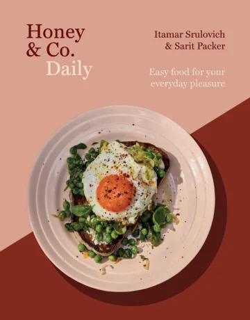 the cover of Honey & Co Daily cookbook is a white plate of toast and greens topped with an egg on top of a rust and dusty rose-colored cover